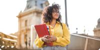 College student holding books looking accomplished and ready for life.