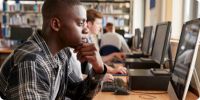 Young adult using a computer to research the college application process.