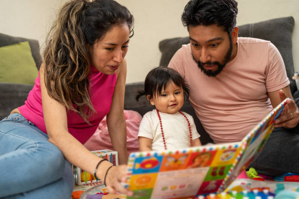 A family with a young child sits on the floor and reads a book.