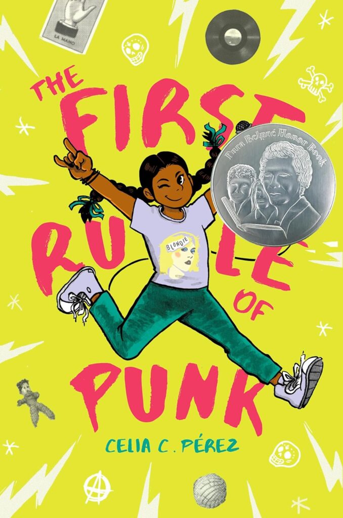 Cover of "The First Rule of Punk." written by Celia C. Perez. A joyful girl with braids jumps, wearing a "Blondie" shirt. 