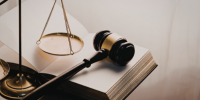 Photo of a gavel, scale, and open book.