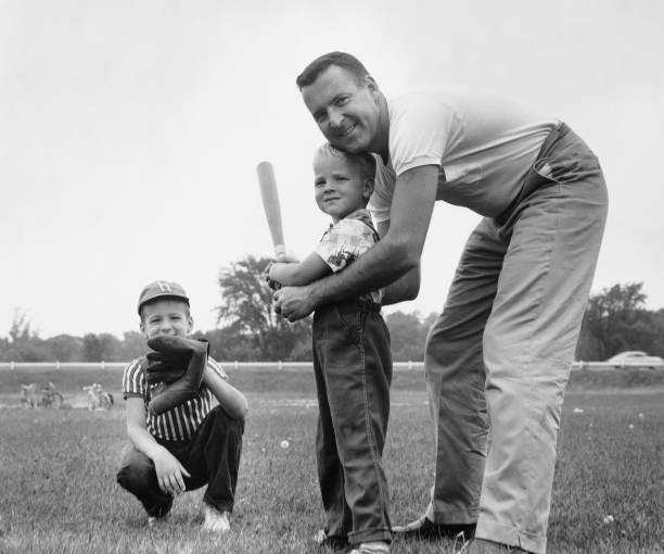 Father and two sons playing baseball in mid twentieth century