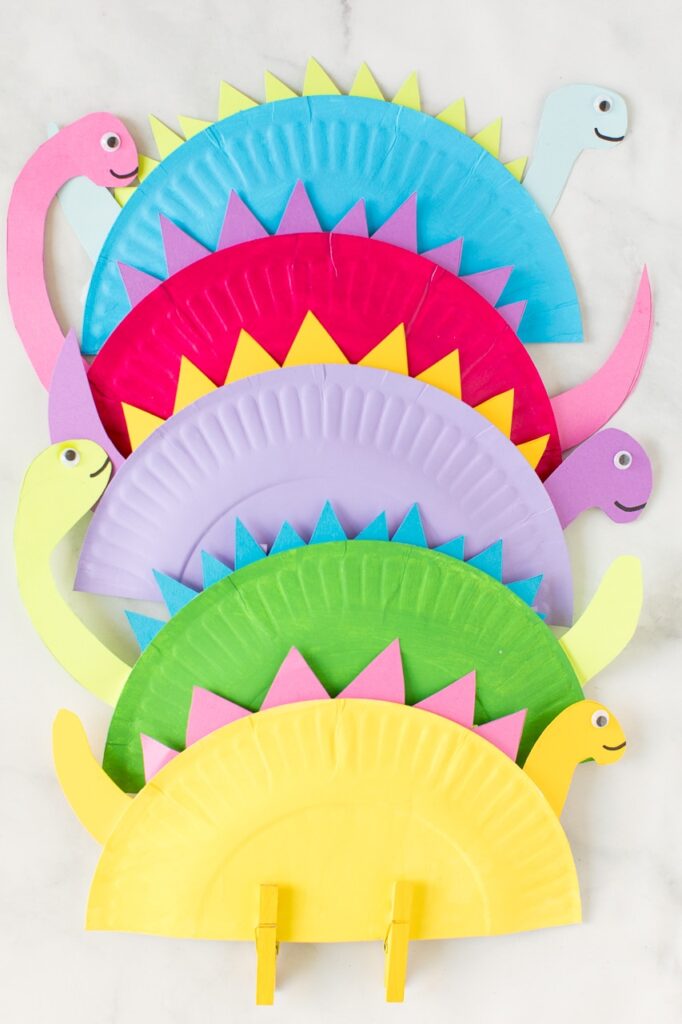 A picture of five paper plate dinosaur crafts, each a different pastel color.
