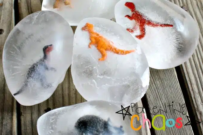 An image of frozen dinosaur toys in ice with the words "parenting chaos" at the bottom right.